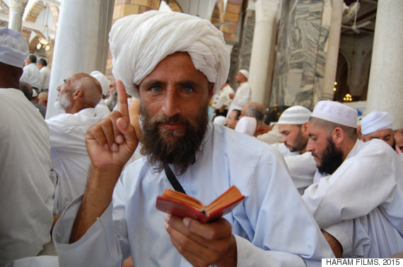 An Afghan 'Hajji' (pilgrim) raises his index finger to denote a central precept of Islam, while holding a Quran in the other hand, during a scene from Parvez Sharma's film "A Sinner in Mecca." Photo courtesy of Haram Films, 2015