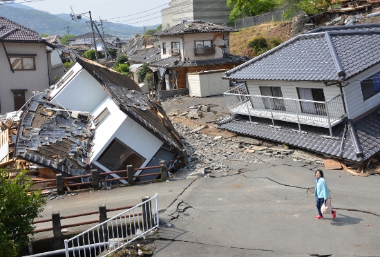 April 19, 2016, Kumamoto, Japan - A woman walks past collapsed houses at Mashiki town in Kumamoto prefecture on Tuesday, April 19, 2016. More than 40 people died and some 1,000 injured as massive earthquakes attacked Japan's southern island of Kyushu. (Photo by Yoshio Tsunoda/AFLO) LWX -ytd-